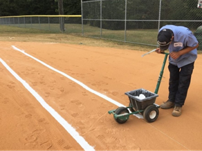 Picture shows one Public Works employee lining a ballfield
